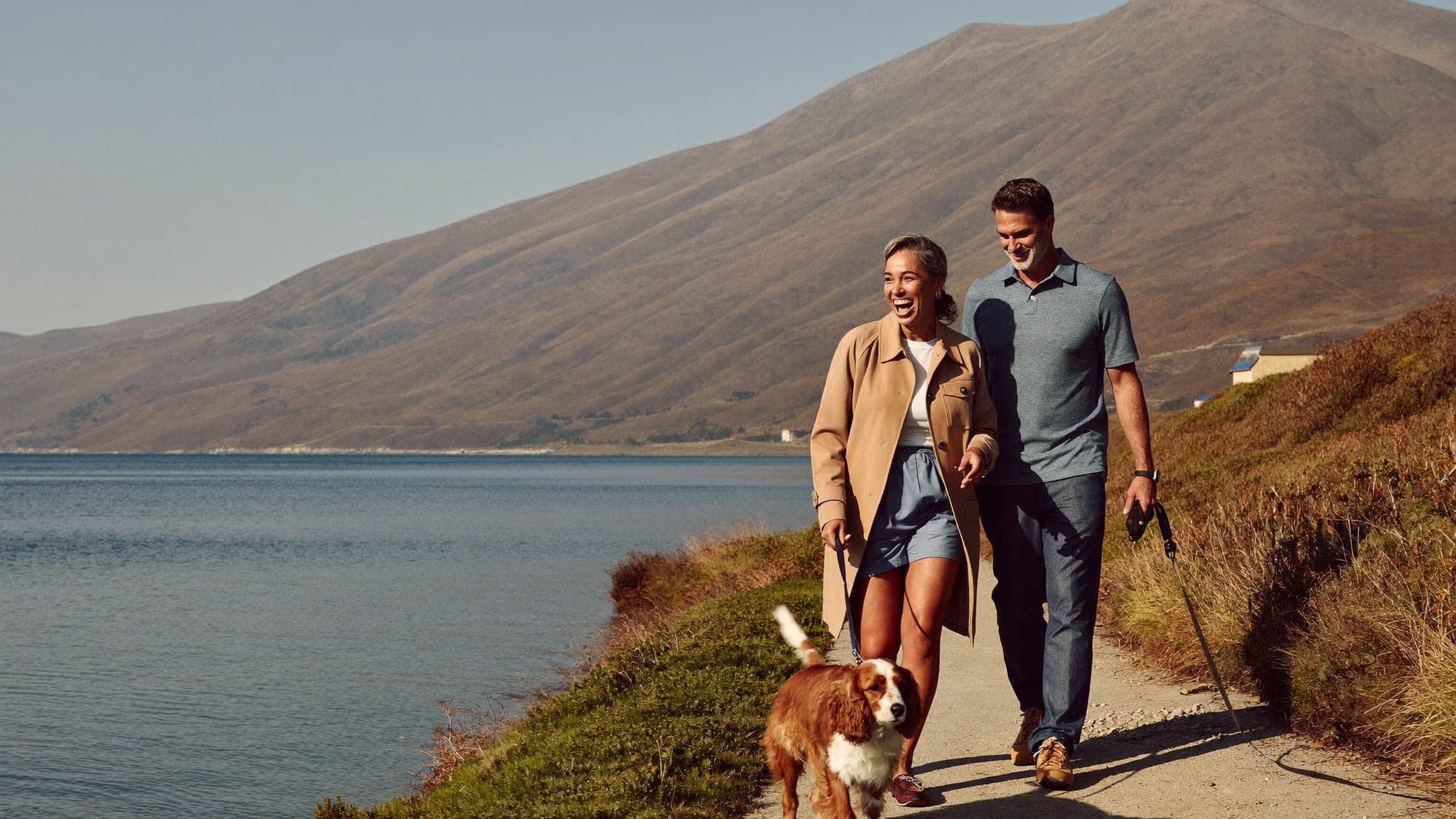 A couple walking their dog by a lake